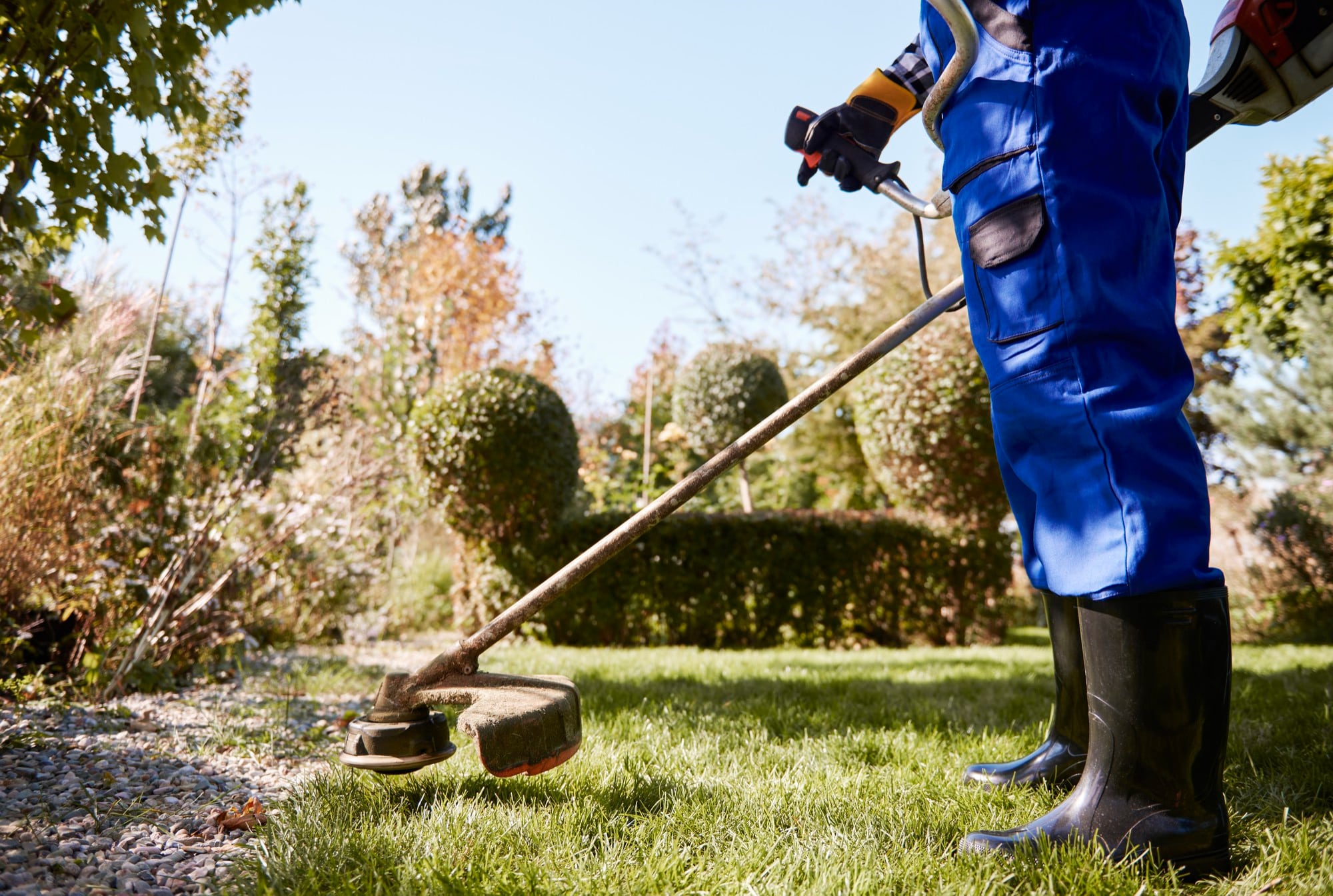 jardinier utilisant un outil motorisé pour débroussailler un terrain